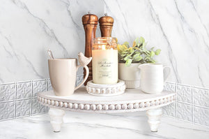 A bathroom tray rests on a corner countertop shelf, accompanied by decorative risers, creating a stylish and organized display.